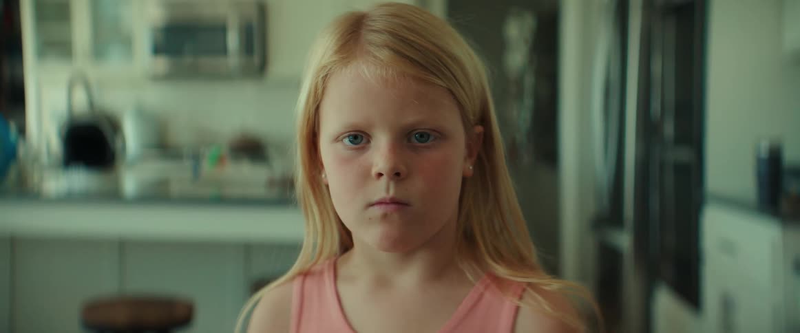 Serious girl standing in the kitchen looking at the camera
