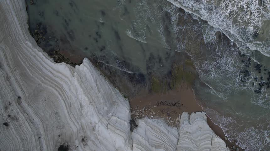 Waves crash against the shore below