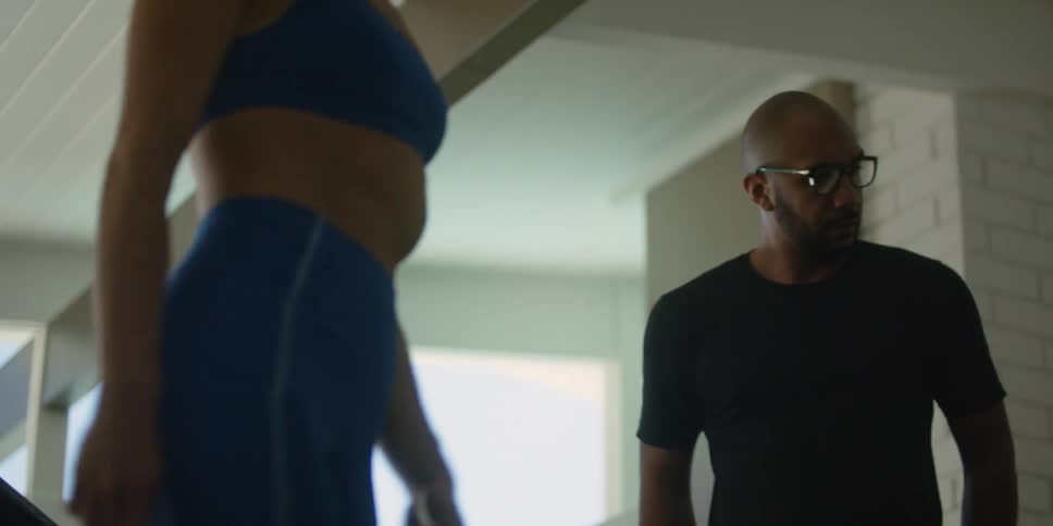 A man instructs a woman in exercise clothing