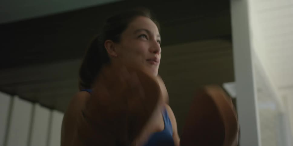 A woman with boxing gloves talks as she gets ready to work out
