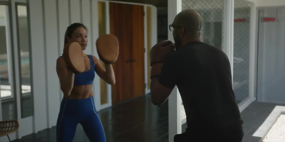 A man wearing boxing gloves strikes the punch mitts being worn by a woman