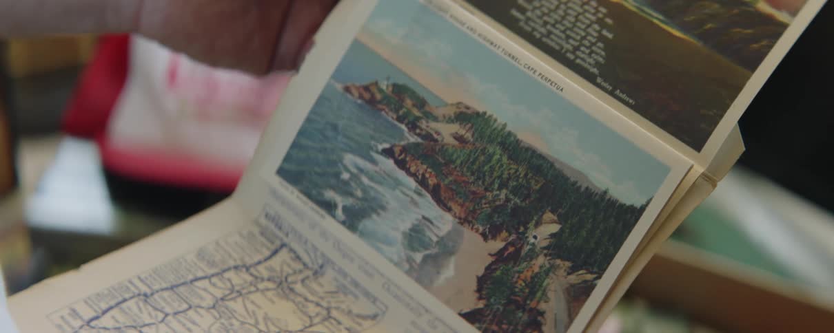 Man looks through scenic booklet from box of keepsakes
