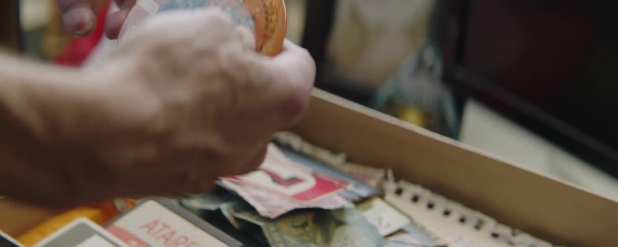 An elderly man looking at a box of trinkets with a pin button