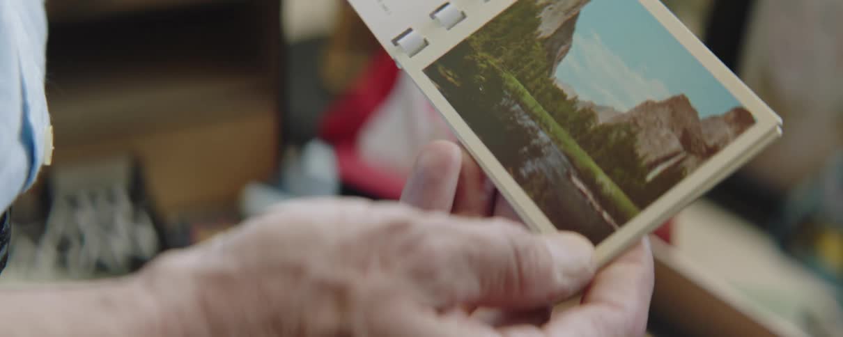 Hand of a man holding a small booklet with vintage postcards of national parks