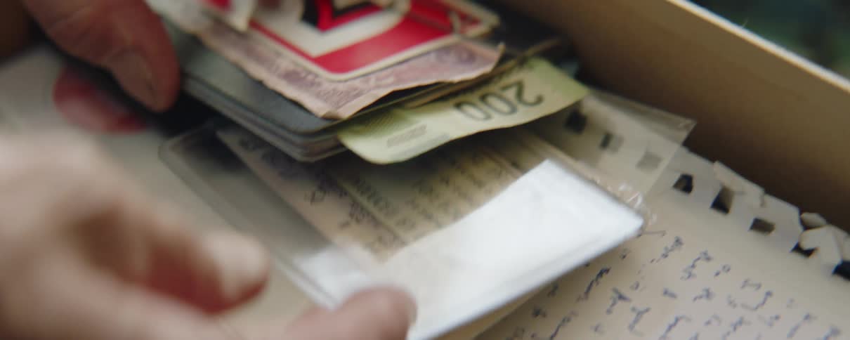 Man pulls sealed ticket out of stack in box of keepsakes