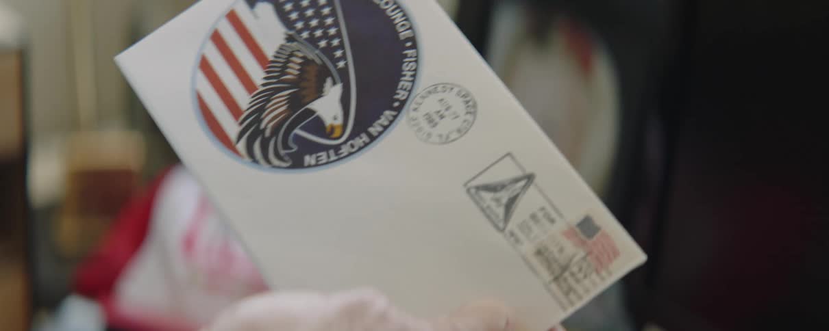 A man is holding a letter with a government emblem and he takes it out of the plastic sleeve