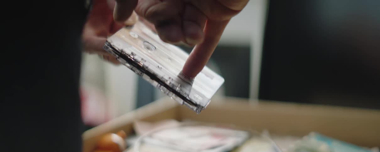 A man puts his finger in a cassette tape and turns it