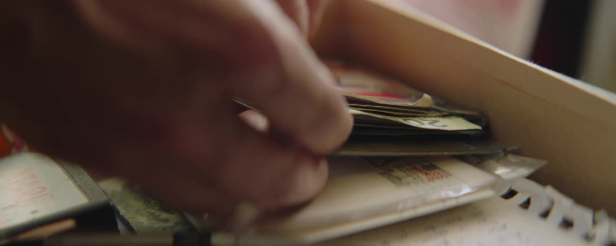Close up of mans hands pulling a card between old banknote in drawer