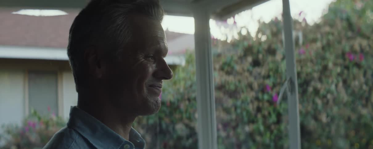Man with gray hair and blue shirt looks out the windows overlooking street