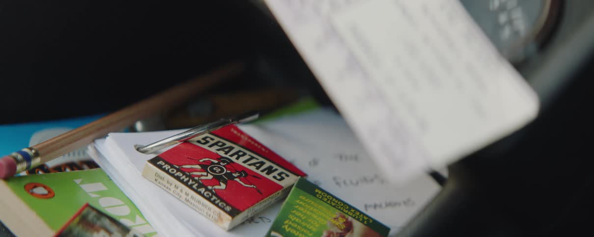An old box of condoms sits on top of a box with notes and books
