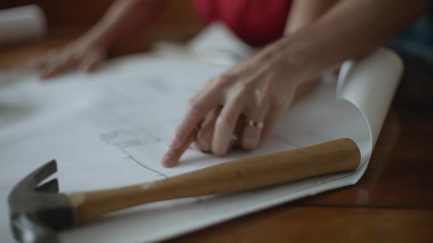 A man and woman go over floor plans on a table