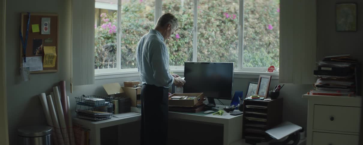Mature man going through the items inside a drawer on the desk at his home office