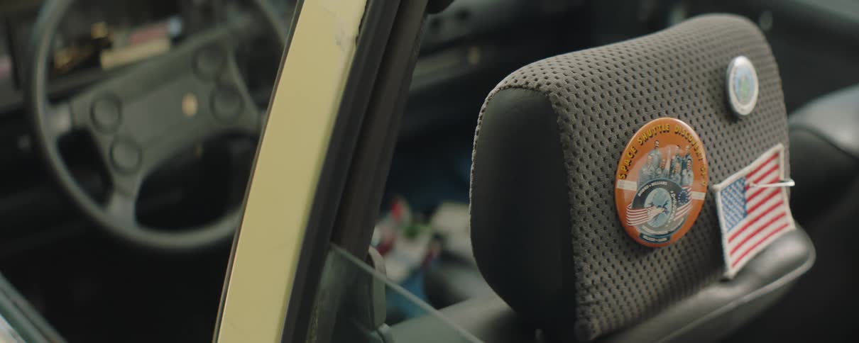 Flag patch and pinback buttons are attached to back of headrest in empty car