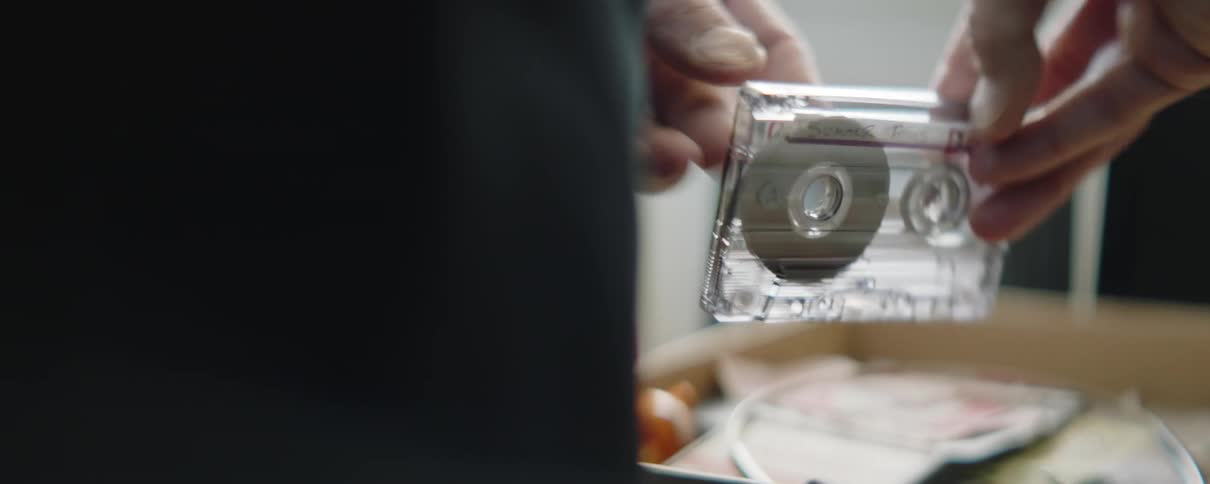 A man picks a cassette up out of a box and runs his fingers over it