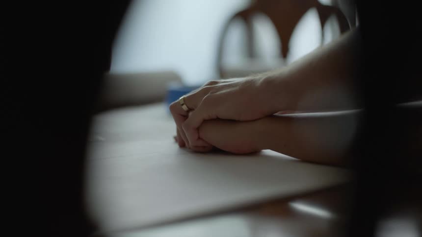 Close up of a couple holding and moving hands over floor plans lying on the dinner table at home