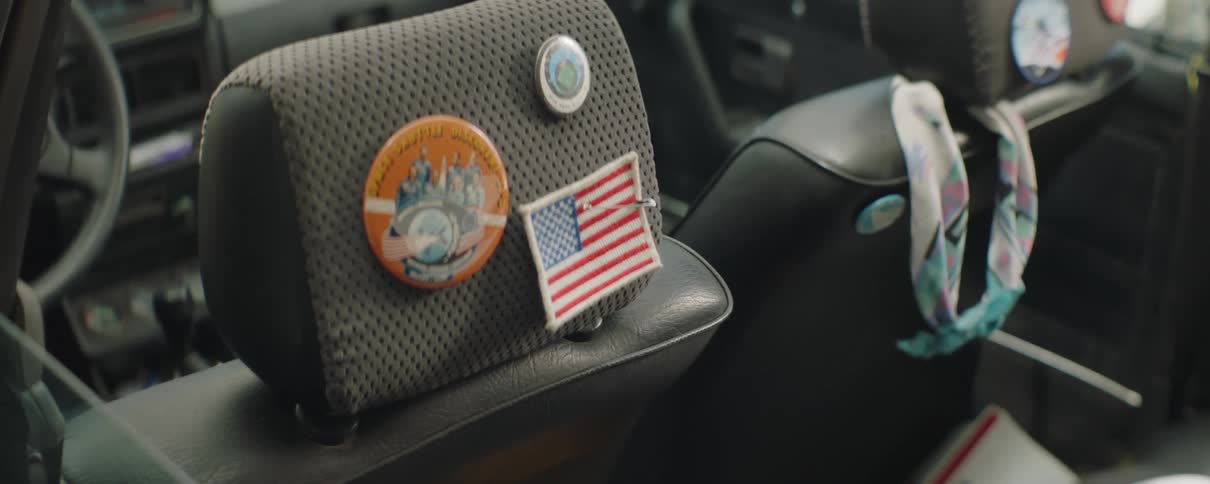 Colorful patches and pins attached to the back of a car's headrest