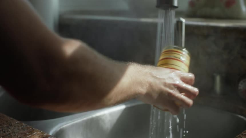 A man washes a glass at home