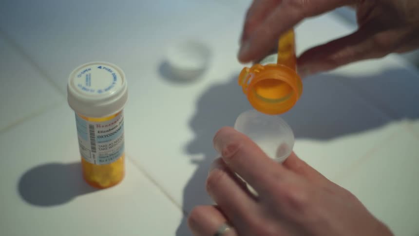 A person pours medication from a bottle