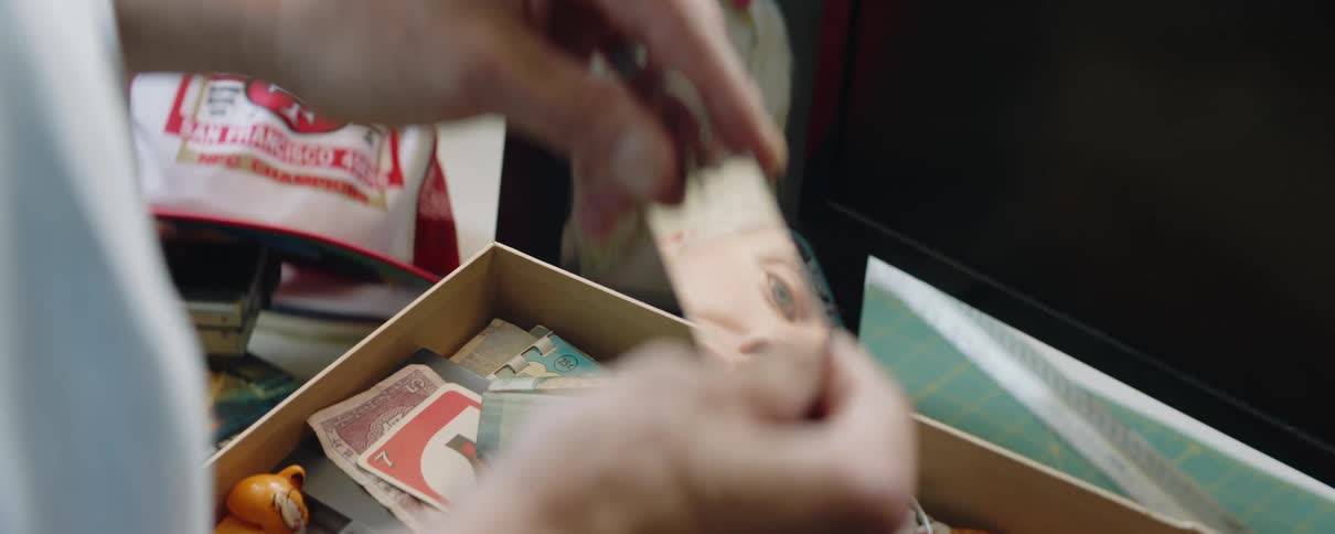 Man standing near box of memorabilia holds keychain that reflects his eyes