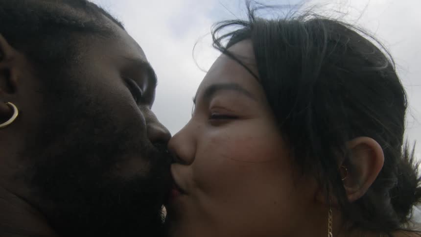 A man and a woman are kissing on a beach
