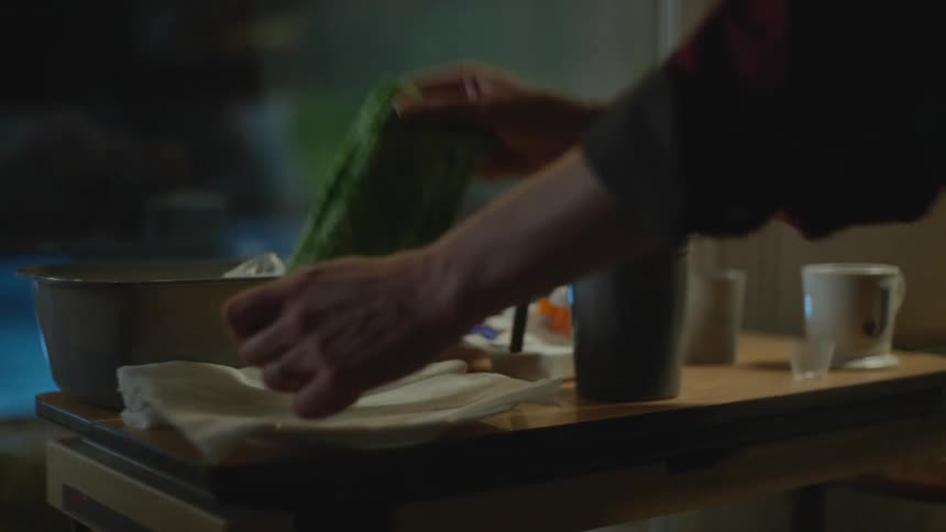 Man taking care of a patient at home takes a green towel from a plate at night