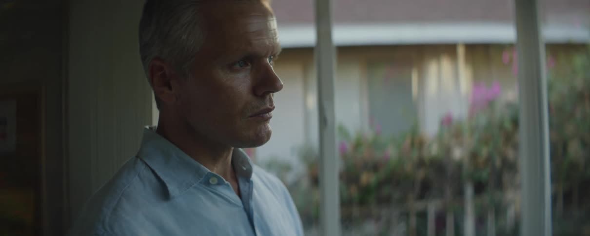 A man stands in front of a window at home and raises his head and looks forward