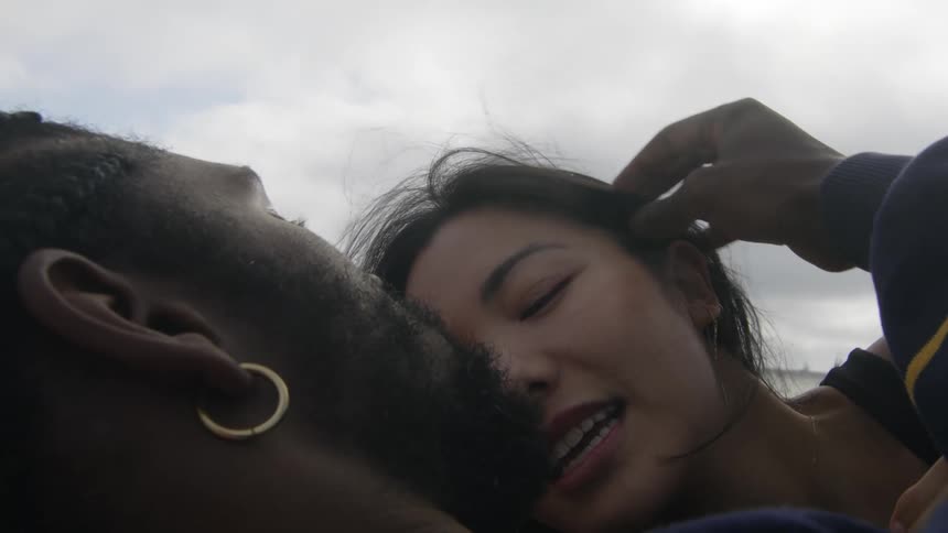 Man with beard and earrings makes out with woman under the clouds