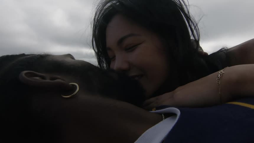 Couple lie on beach and kiss on an overcast windy day