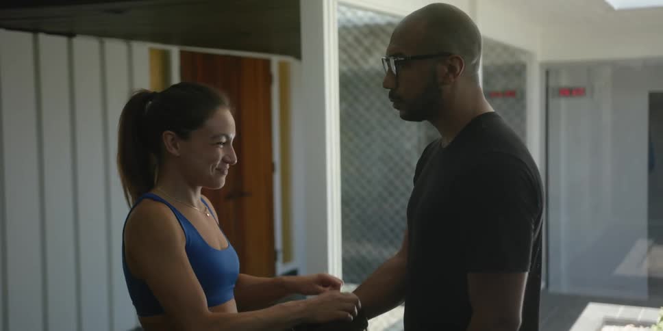 A trainer ties a boxing glove onto her clients hand