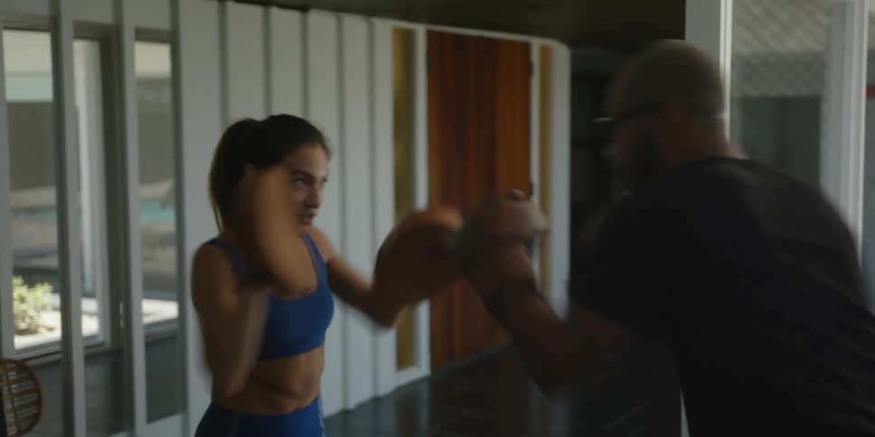 A woman is wearing boxing mitts as a man is boxing with her