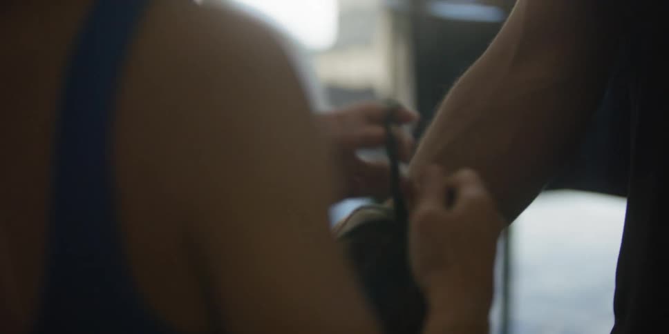 Female trainer ties the laces on the boxing gloves of her trainee