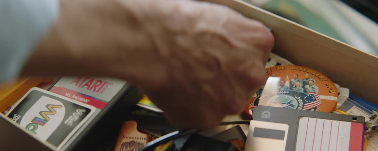 Man rummaging on a drawer filled with vintage items picks up a postcard