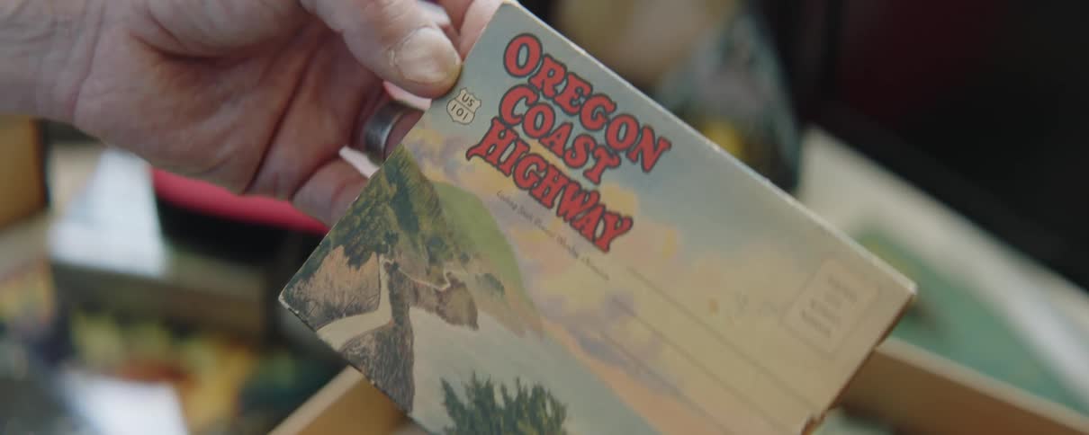 Hand of a man holding a small booklet with vintage postcards of national parks