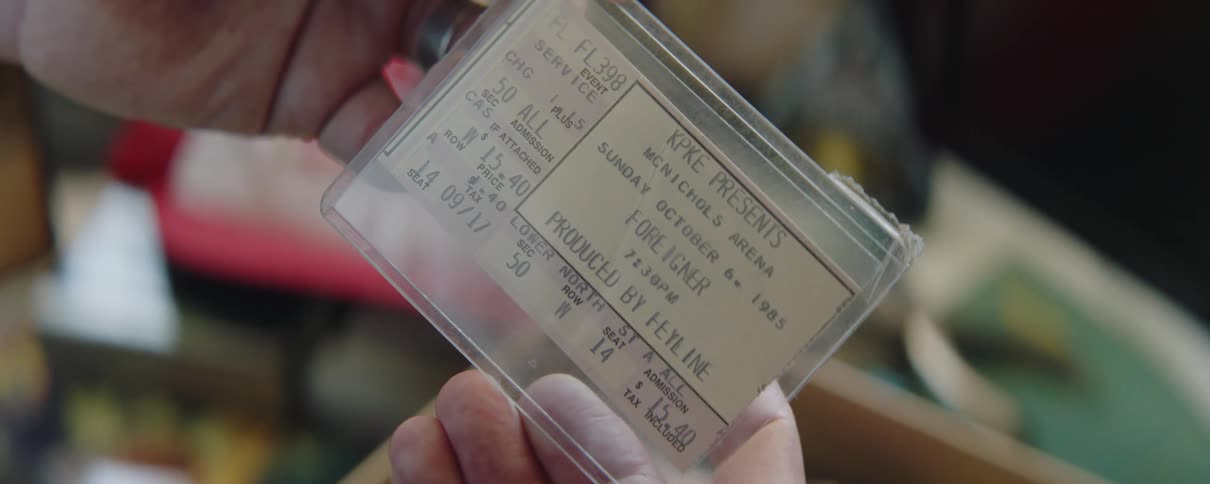 Person stands looking at preserved concert ticket
