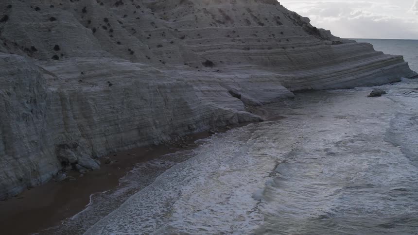 Waves roll onto a beach on a cloudy day