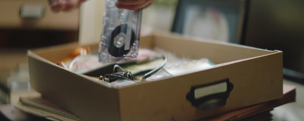 A man takes a cassette tape out of a box and he is holding it in his hands