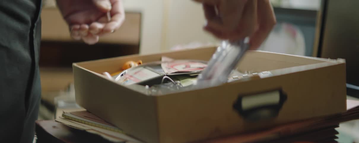 Man stands looking through drawer of memorabilia and keepsakes
