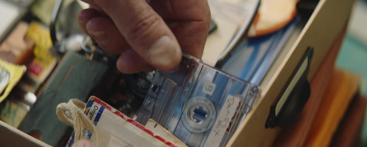 A man takes a homemade cassette tape out of a box filled with mementos