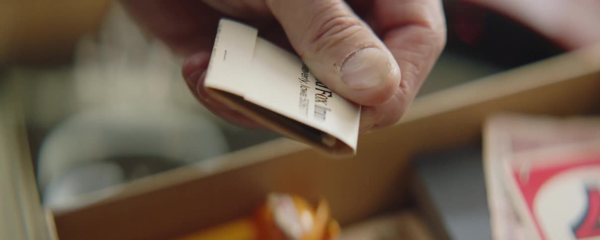 Man rummaging on a drawer filled with vintage items picks up a book of matches