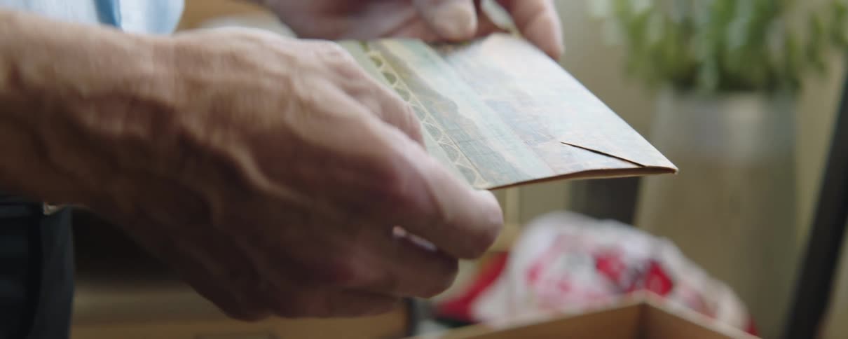 Elderly man searching through the vintage object inside a drawer picks up a postcard