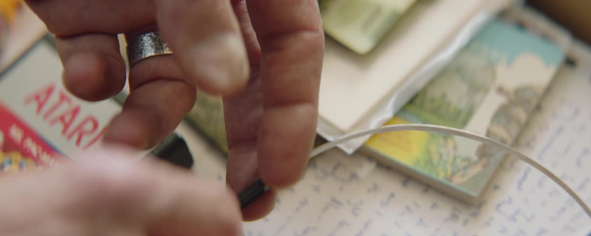 A man fingers vintage style headphones while going through a box of mementos