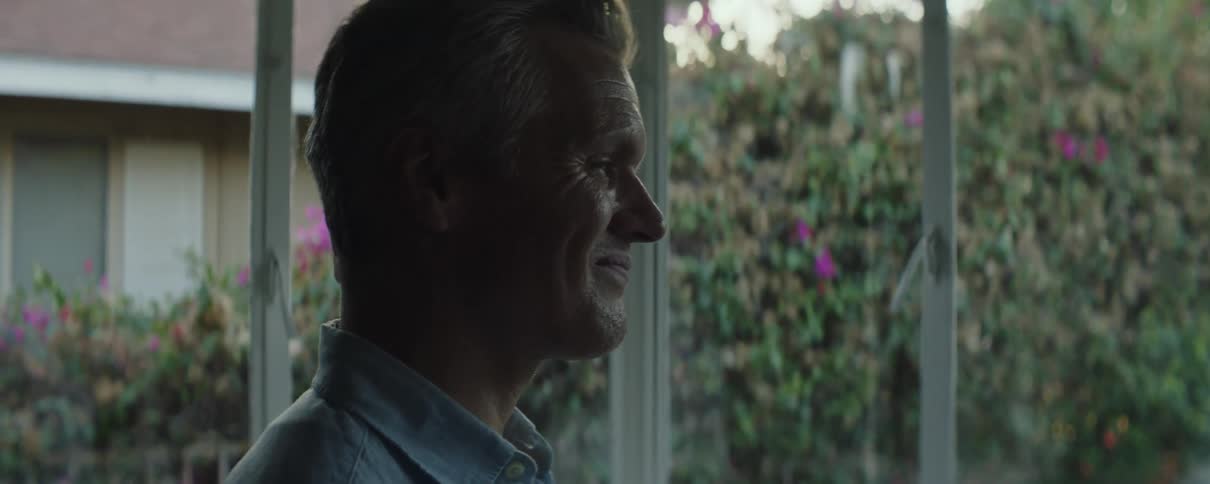 A man smiles while standing in his screened in porch