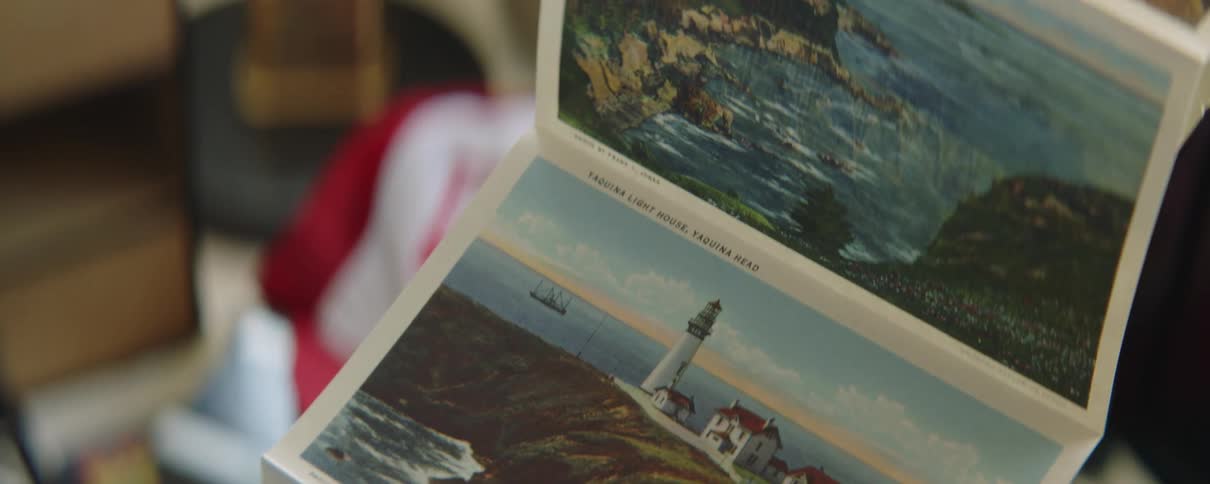 Man examines series of connected scenic postcards while standing near keepsake box