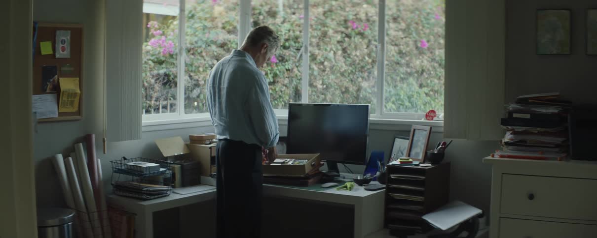 Mature man going through the items inside a drawer on the desk at his home office