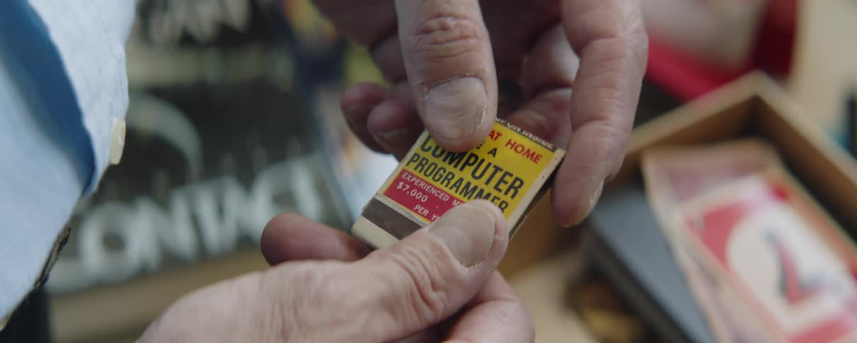 Close up of the hands of an elderly man inspecting a vintage book of matches