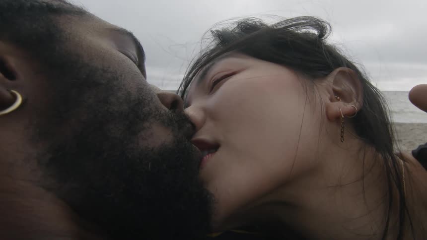 Man and woman are kissing outdoors by the beach