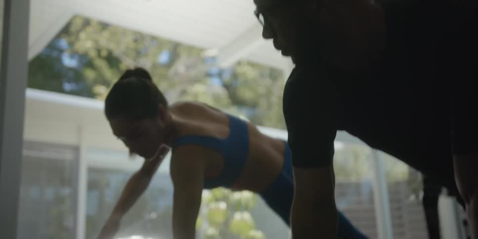 Man follows womans actions as they exercise