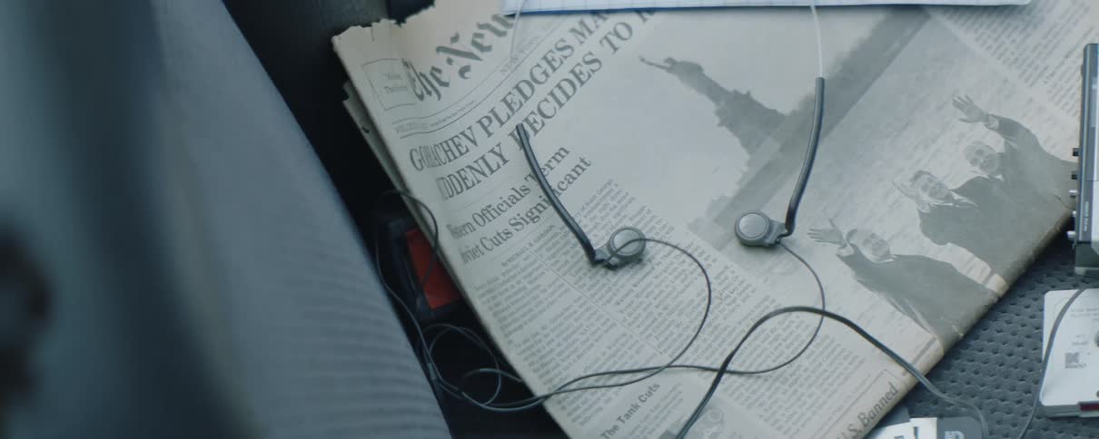 Headphones and old cassette player lie on seat near old newspaper and a cassette