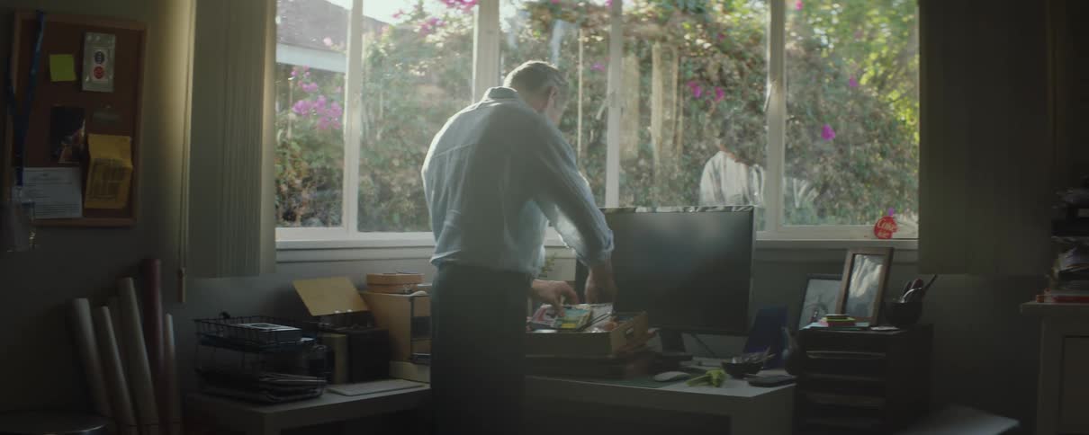 A man goes through a box of papers while standing at his desk at home
