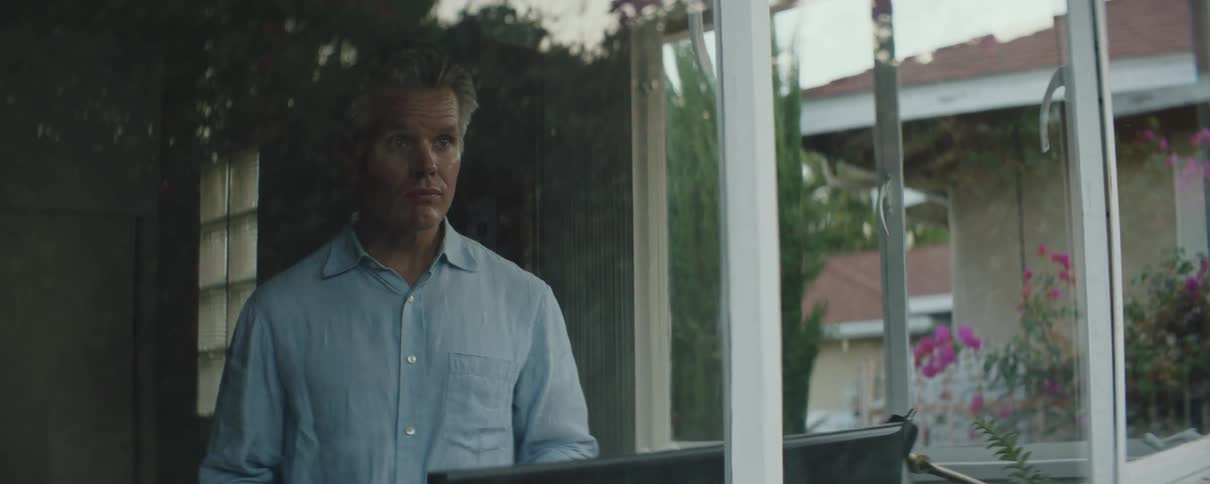 Mature man looking at the porch from the window of his studio at morning
